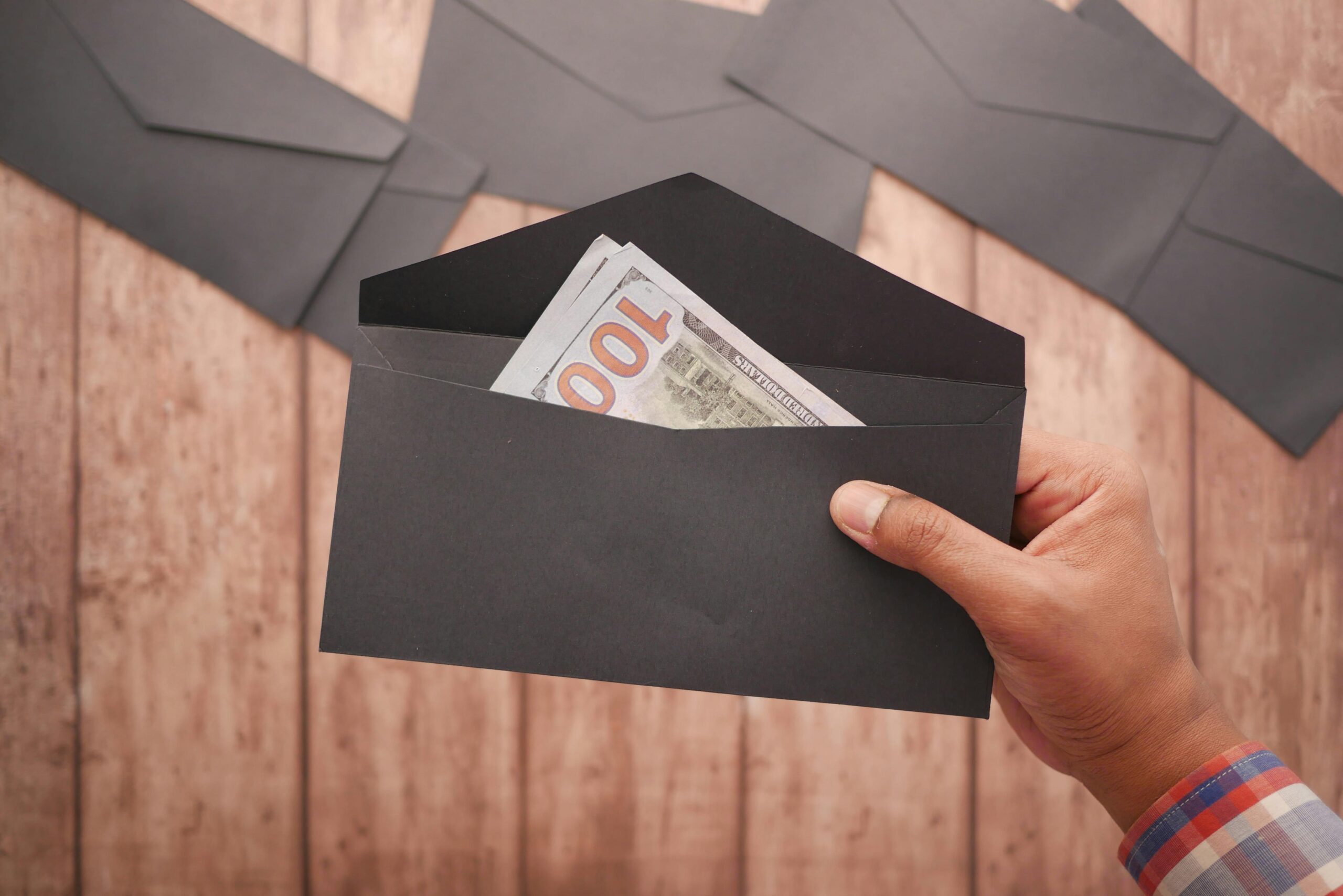 Photo by Towfiqu barbhuiya: https://www.pexels.com/photo/a-person-holding-a-black-envelope-with-money-11327902/